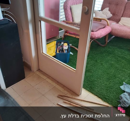 דלת עם זכוכית חסרה וכלי עבודה על הרצפה